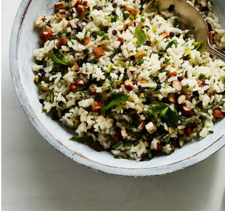 Brown rice salad in a wooden bowl with toasted nuts, currants and parsley